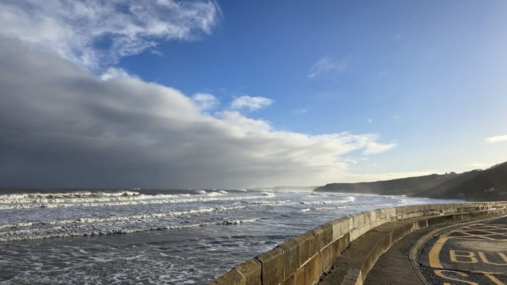 Rolling beach waves by road.